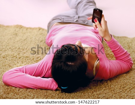 Woman look at phone, lying on the carpet