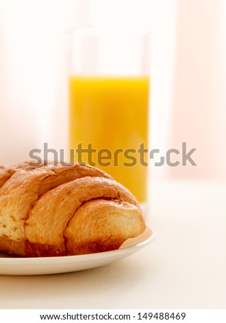 Glass of refreshing orange fruit juice and croissant over business paper