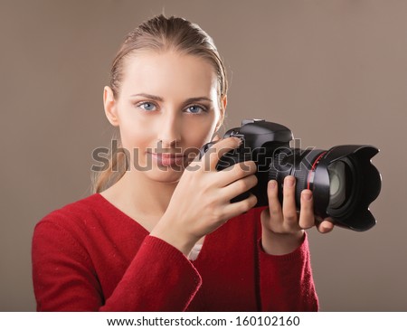 Beautiful young woman with camera. isolated on grey background