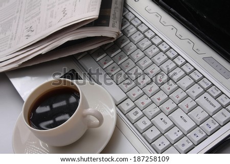 coffee cup on a newspaper near the laptop