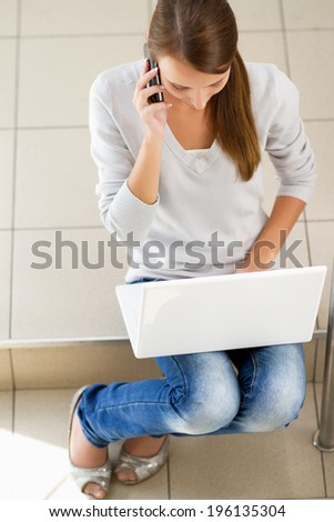 Young woman sitting with laptop and talking on the phone,Isolated on white background