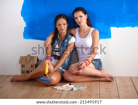 Two Happy beautiful young women doing wall painting,
