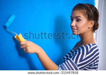Happy beautiful young woman doing wall painting,