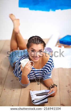 Portrait of female painter lying on floor near wall after paint
