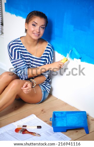 Happy beautiful young woman doing wall painting,sitting on the