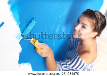 Beautiful young woman doing wall painting, standing