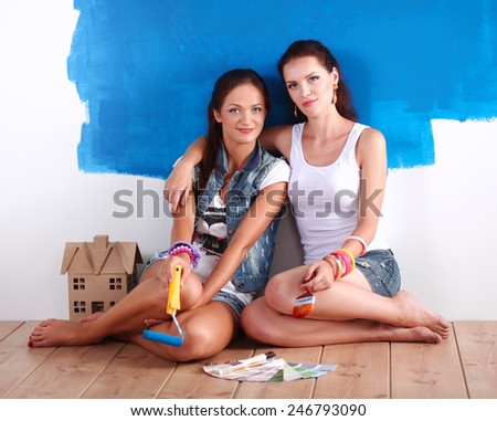 Two Beautiful young woman doing wall painting, sitting
