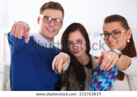 Young business people standing at office near desk and pointing you.