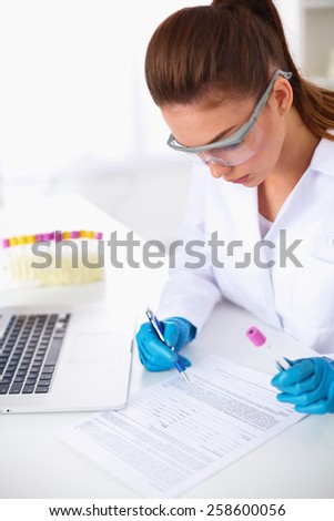 Woman researcher is surrounded by medical vials and flasks, isolated on white