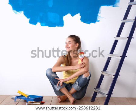 Portrait of female painter sitting on floor after painting.