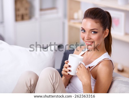 Portrait of oung beautiful woman with a cup on sofa at home