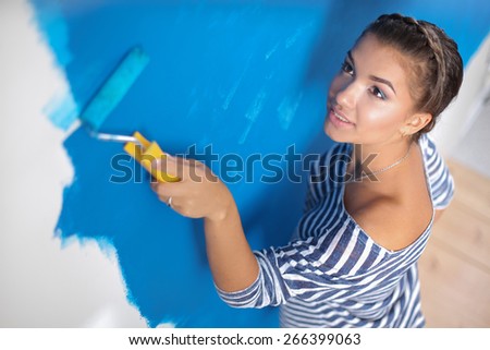 Beautiful young woman doing wall painting, standing
