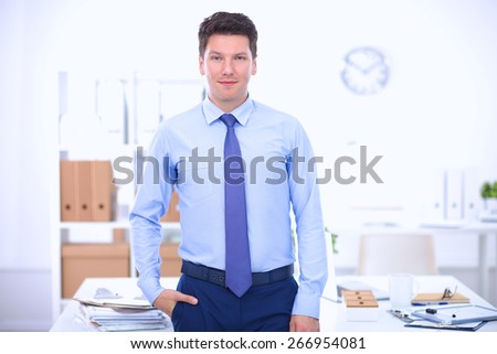 Business man or manager standing against his desk at the office.