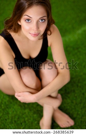 Woman sitting with crossed legs on the green grass .