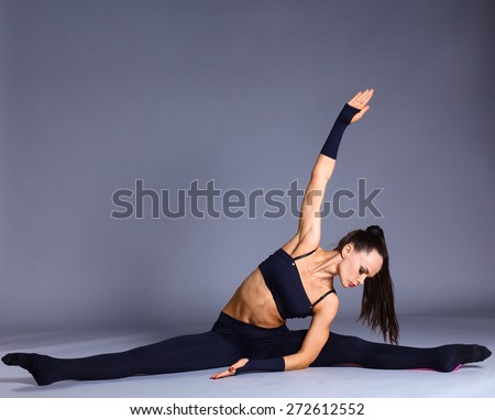 Young attractive female fitness woman performing a twine .