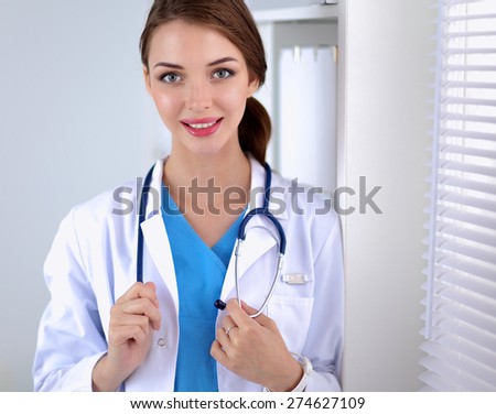 Woman doctor is standing near window with crossed arms,isolated.