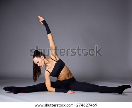 Young attractive female fitness woman performing a twine