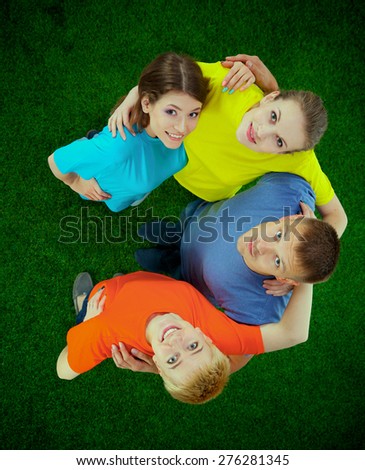 Group of young people lying on green grass.