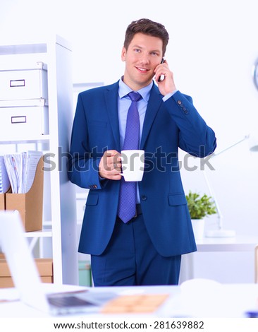 Smiling businessman standing and using mobile phone