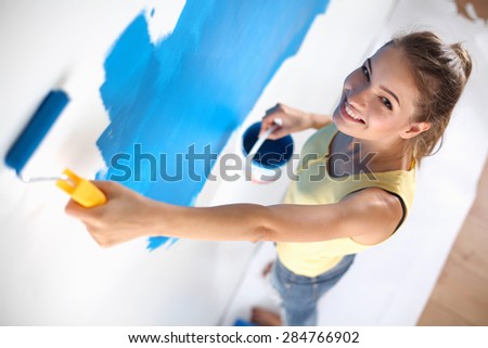Beautiful young woman doing wall painting .
