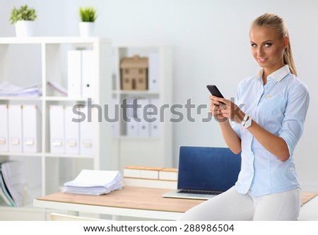 Young business woman standing in office talking on her mobile phone.