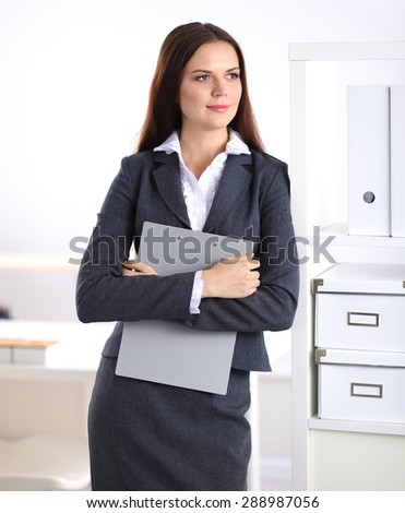 Attractive businesswoman standing near desk in the office