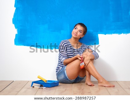 Portrait of female painter sitting on floor after painting.