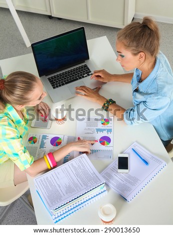 Two women working together at office, sitting