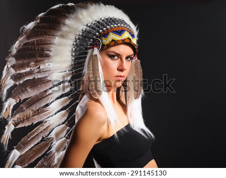 Beautiful woman in native american costume with feathers .