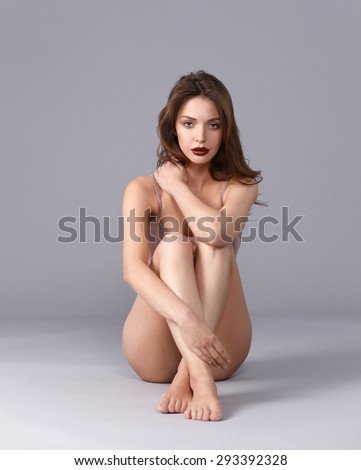 Beautiful barefoot woman sitting on the floor .