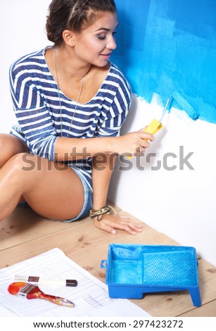 Beautiful young woman doing wall painting, sitting