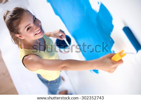 Beautiful young woman doing wall painting .