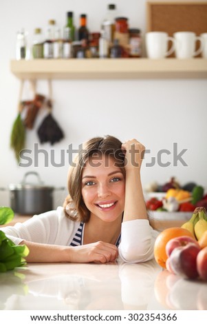 Young woman standing near desk in the kitchen .