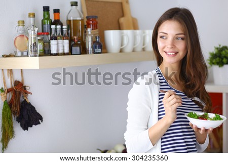 Young woman eating salad and holding a mixed salad .