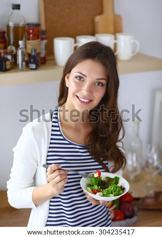 Young woman eating salad and holding a mixed salad .