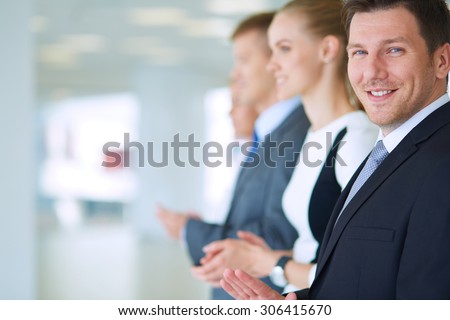 Smiling business people applauding a good presentation in the office .