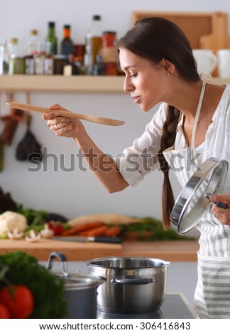 Cooking woman in kitchen with wooden spoon.