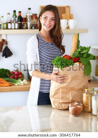 Young woman holding grocery shopping bag with vegetables .