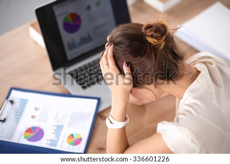 Portrait of tired young business woman with laptop computer at the office