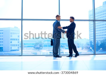 Full length image of two successful business men shaking hands with each other