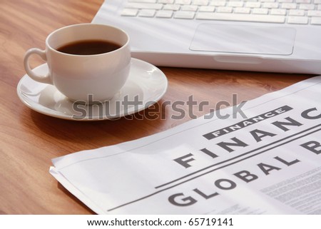 coffee cup on a newspaper near the laptop