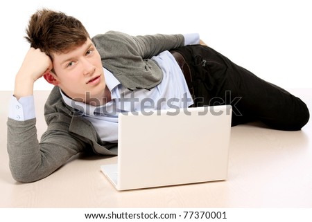 A young college guy lying on the floor with a laptop