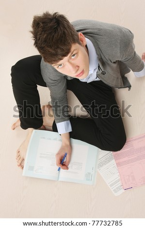 A young handsome college guy sitting on the floor and studying, from above