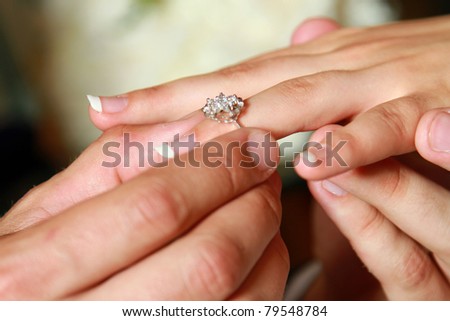 Closeup of hands of a bride and a groom, a man putting a ring on his woman\'s finger