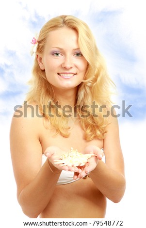 A young woman on the beach holding a shell in her hand