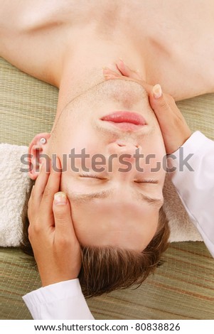 A female hands massaging  man\'s face in a spa center