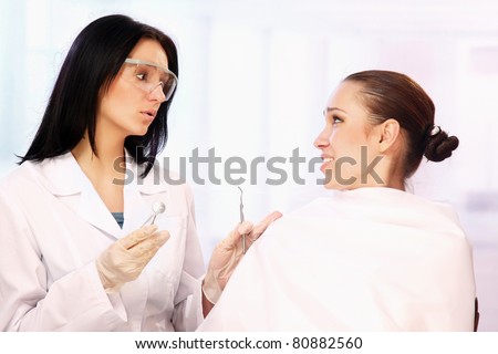 A female dentist is calming a patient in the cabinet