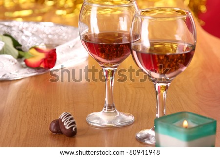 A celebratory dinner with a rose, candle,  two glasses of red wine