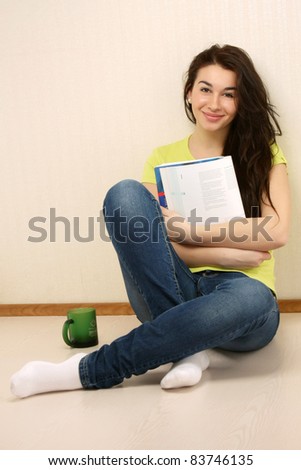 Young student girl reading book against the wall