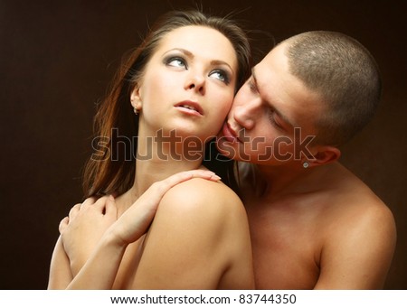 Closeup portrait of young passionate couple in love over dark background